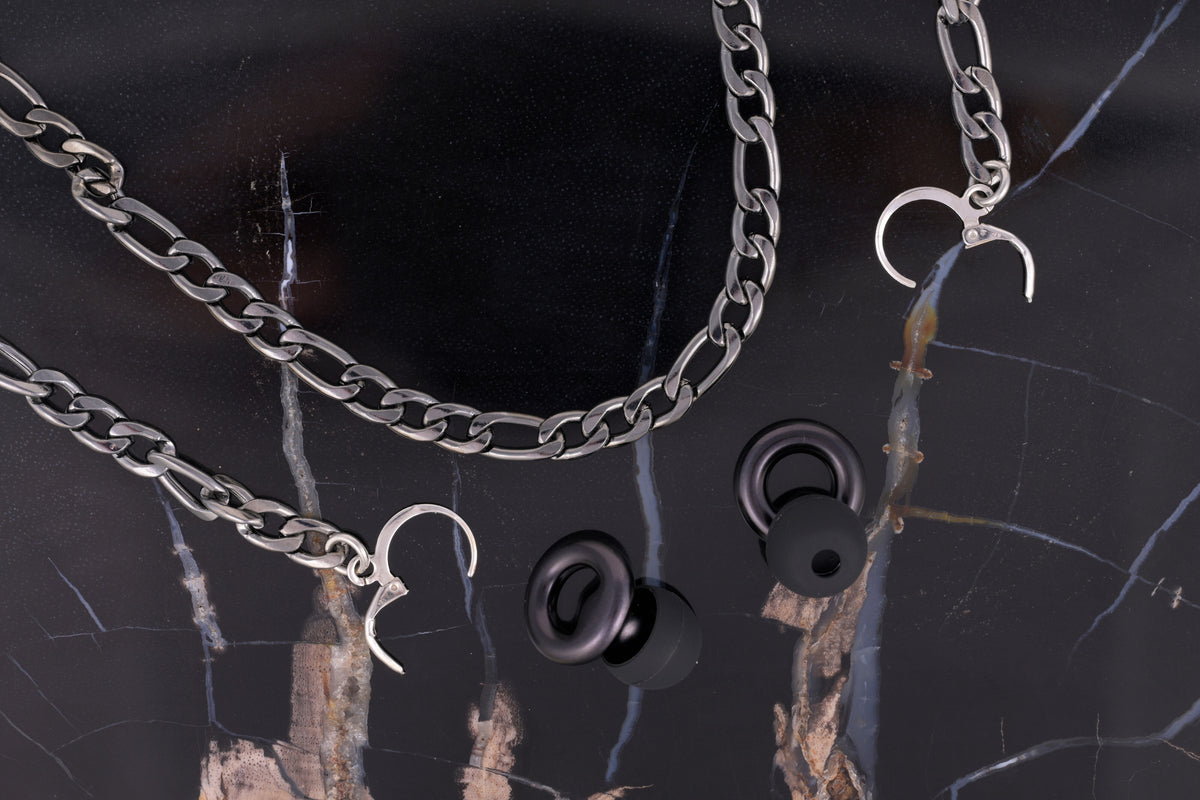 The gold ARKS chain laid out at full length, an earplug on each drop strand.