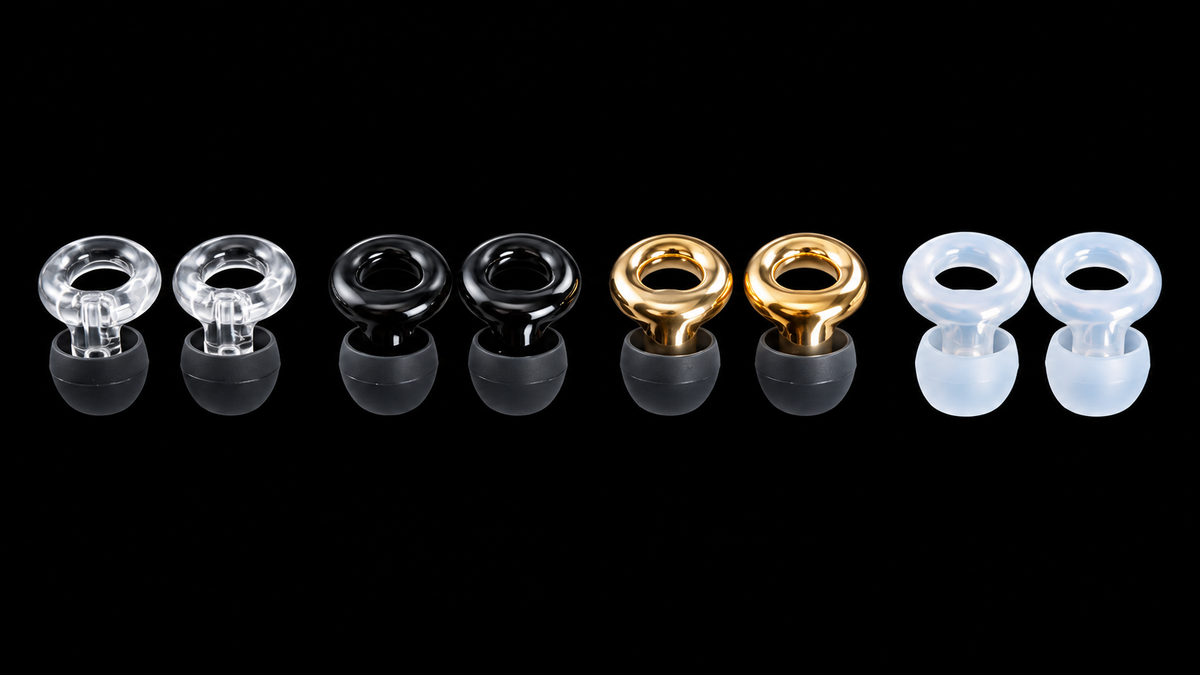 Four matte black ARKS earplugs, two with gold rings and two with black rings.