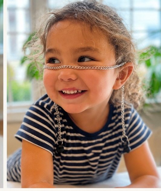 A young child smiling, wearing an ARKS chain as a face chain.