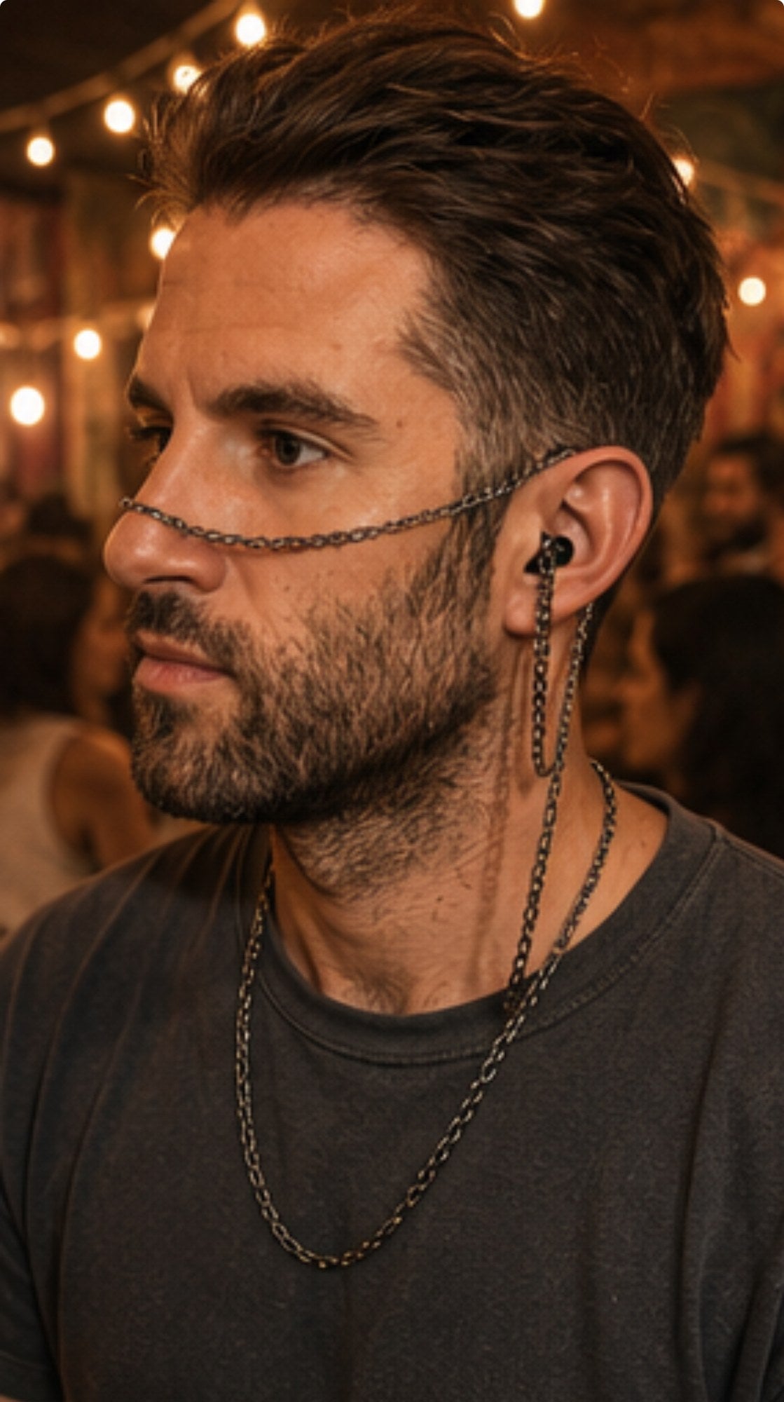 A man wearing ARKS as a face chain indoors, warm lights behind him.
