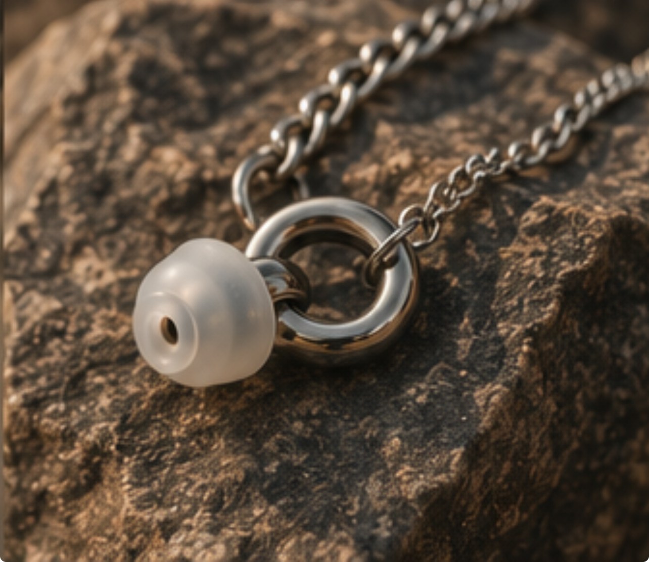 Macro of the ARKS ring and earplug on stone.
