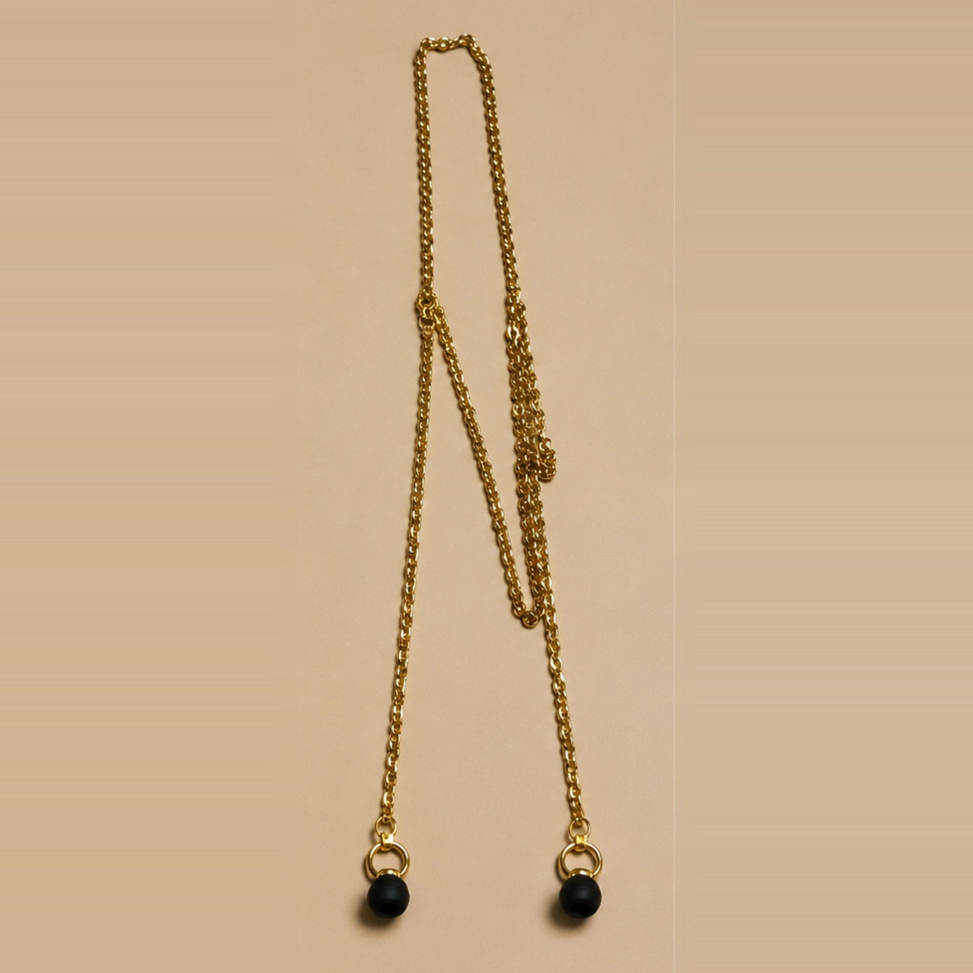 The gold ARKS chain laid out at full length, an earplug on each drop strand.